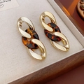 Detail von Gliedohrringen aus Gold und Schildpatt-Resin auf einer beigen Schmuckbox - Stil 1 (Gold-Braun Kette)