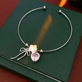 Detailed close-up of a silver bow and pink heart charm bracelet on a green leather box - Silver (Bracelet)