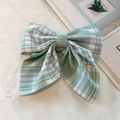Elegant green and white checkered bow hair clip on a minimalist fabric background - Cedar Plaid