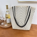 Detail of cream knitted tote bag with black V-shaped patterns on a wooden table - 1 Dotted Line Beige