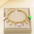 Dettaglio di bracciale in acciaio dorato con ciondoli a forma di frutta colorata su portagioie - Stile Mela Limone Cuore (KB203064-Z)