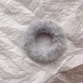 Top view of a fluffy light grey faux fur scrunchie on a white textured paper background - Grey Blue