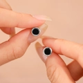 Paio di orecchini a lobo minimalisti in onice nera e argento tra le dita della mano - Argento 925 / Onice Nero Placcato Argento