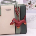 Detail of red leather dachshund charm with orange paws hanging on a stylish handbag - Burgundy
