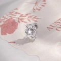 Silver hollow bear earring with blue star zircon inlay, displayed on vintage paper - White