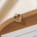 Vista macro del ciondolo a cuore dorato con strass su vassoio di legno marrone - Piccolo cuore traforato