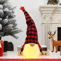 Gnomo de Navidad con luz y gorro de cuadros rojos en mesa decorada festiva - Estilo de Cuadros Rojos