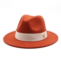 Macro view of burnt orange wool fedora hat with beige ribbon and gold logo metal buckle - Brick Red