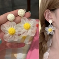 Vista macro detallada de pendientes de flores de rafia hechos a mano en la oreja y mano - Beige Amarillo