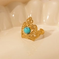 Detail of golden crown ring featuring a turquoise stone on a shell display - Turquoise-Gold