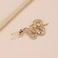 Dettaglio di un fermaglio per capelli a serpente dorato con squame e occhi di gemme nere - Oro