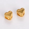 Detailed close-up of golden heart-shaped earrings with unique vertical striped relief design - Gold