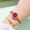 Detail view of a luxury gold women's watch with red dial and sparkling rhinestone accents - Red