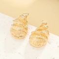 Macro shot of gold spiral shell earrings with textured finish on a white stone background - Gold Conch Style (N-203)