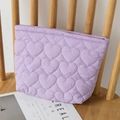 Detailed texture of purple heart quilted nylon fabric pouch on a wooden chair - Purple