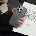 Detail of silver glitter phone case with metallic edges held by a hand near a bag - Black and Gray / US 15