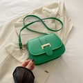 Minimalist green leather crossbody bag with gold metal clasp on a beige blazer - Green