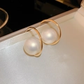 Primer plano de pendientes de aro dorados con grandes perlas blancas en un joyero beige - Pendientes de Perlas Doradas en Forma de C (Pin de Plata)