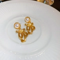 Elegant gold plated bowknot earrings with white pearls on a ceramic display - Gold Bowknot Dynamic Pearl Style (38#)