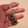 Porte-clés beignet réaliste et créatif avec chaîne en métal tenu à la main sur fond beige - Décoration de vermicelles / Brun