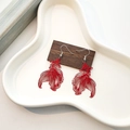 Detail view of red hollow goldfish drop earrings on a dark wood display stand - Hollow Red Goldfish