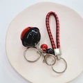 Close-up of a woven leather cord keychain with red and black bells on a tray - Red & Black