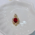 Elegant gold pendant with oval red gemstone and clear rhinestones on white plate - Red Flower