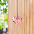 Pink heart-shaped crystal suncatcher pendant hanging on black string with wood background - 45mm / Pink