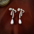 Detail of silver bow earrings with sparkling rhinestones and teardrop pearls on brown satin - Bowknot Waterdrop Pearl Earrings (2#) / Silver