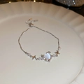 Detail van kattenoog hart armband met ster hangers op wit keramisch bord - Zilveren Hart