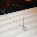 Detalle de collar dorado minimalista con perla brillante y colgante de circonita radiante - Oro-Blanco