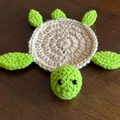 Handmade crochet turtle coaster with beige shell and green limbs on dark wood table - Off-white & Neon Green
