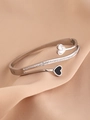 Detailed close-up of silver titanium steel heart bangle with white and black heart charms - Silver