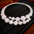 Detailed close-up of oversized faux pearls with silver spacers on a textured jewelry tray - White Pearl Choker