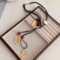 Long ethnic necklace with gold leaf charms and large baroque pearl on black cord - Alloy/Baroque Pearl/Beads