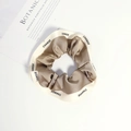 Close-up of a satin scrunchie with CHANGE lettering next to an aesthetic book - Brown