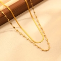 Détail d'un collier double épaisseur doré avec breloques cœur et étoile sur support en bois - Collier à Lame Double Couche Étoile Coeur Doré (T307)