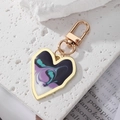 Detail of a heart-shaped gold alloy keychain featuring purple fluid art on white rock - Black Purple