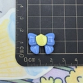 Close-up of blue resin bow with yellow anchor emblem on a measuring mat - Blue Bow