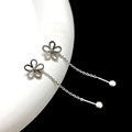 Dettaglio macro di orecchini a fiore d'argento con nappa su base di ceramica - Catena per orecchio a fiore cavo color acciaio