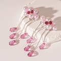 Makro-Detail von rosa Perlenblumen-Ohrringen mit langen Kristall-Quasten auf weißem Stein - Silberne Nadel - Rosa Wolken-Quasten-Ohrringe