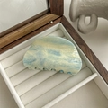 Detail shot of marble textured gradient hair claw clip in a velvet jewelry display box - Ink Blue