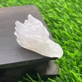 Carved natural white crystal dragon head figurine on wood base with outdoor lawn background - Rose Quartz