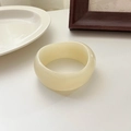 Minimalist wide resin bangle in creamy beige finish shown on a white ceramic plate - White