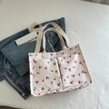 White canvas tote bag with red cherry print featuring double front pockets and straps - White