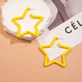 Gros plan de boucles d'oreilles étoiles en acrylique jaune sur un socle décoratif - Jaune