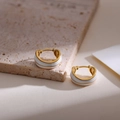 Gros plan de boucles d'oreilles dorées avec émail blanc sur socle en pierre - Blanc