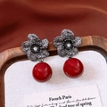 Dettaglio macro di orecchini vintage a fiore con petali scuri e pendente a sfera rossa - Perno per orecchini in argento - Canna di fucile - Rosso