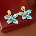 Detalle de pendiente floral con pétalos azules, perlas y metal dorado en caja de madera - Azul