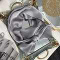 Macro detail of a grey 100% mulberry silk skinny scarf tied on a luxury mirror tray - 15x150cm / Light Gray